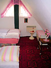 Růžový čtyřlůžkový pokoj ve špici chalupy.